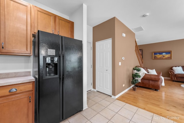 5611 Wildspring Dr, Lake In The Hills, IL 60156 - kitchen featuring black refrigerator with ice dispenser, open floor plan, light tile patterned flooring, light countertops, and brown cabinetry
