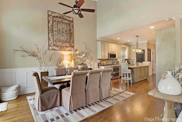 3334 N Odell Ave, Chicago, IL 60634 - dining space with a ceiling fan, light wood-style floors, a chandelier, a wainscoted wall, and crown molding