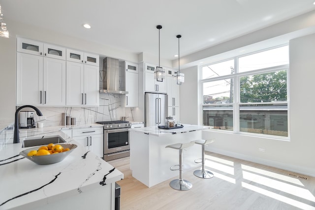 3450 N Central Ave, Chicago, IL 60634 - kitchen featuring high end appliances, wall chimney range hood, a sink, a kitchen bar, and light wood finished floors