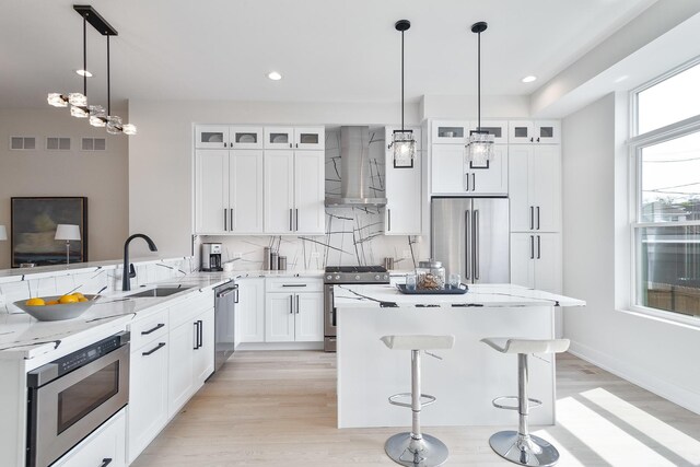 3450 N Central Ave, Chicago, IL 60634 - kitchen with appliances with stainless steel finishes, wall chimney exhaust hood, a sink, a kitchen island, and light stone countertops