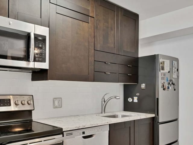 440 N Wabash Ave Unit 2008, Chicago, IL 60611 - kitchen featuring appliances with stainless steel finishes, a sink, dark brown cabinets, tasteful backsplash, and light stone counters