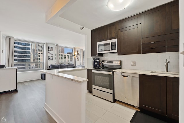 440 N Wabash Ave Unit 2008, Chicago, IL 60611 - kitchen featuring appliances with stainless steel finishes, dark brown cabinets, a sink, and decorative backsplash
