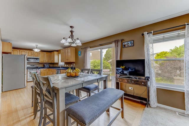 1715 Ivy Ln, Montgomery, IL 60538 - dining space with a chandelier, baseboards, and light wood-type flooring