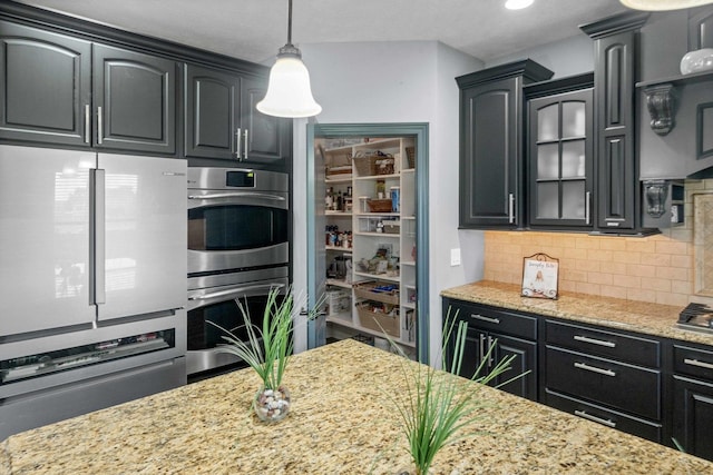 4 Emerald Crest Ct, Bloomington, IL 61705 - kitchen with appliances with stainless steel finishes, backsplash, light stone countertops, glass insert cabinets, and hanging light fixtures