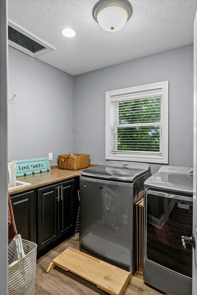 4 Emerald Crest Ct, Bloomington, IL 61705 - laundry room featuring washer and clothes dryer, cabinet space, light wood-style flooring, and a textured ceiling