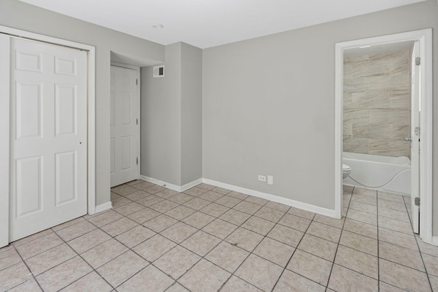 6344 S Rhodes Ave, Chicago, IL 60637 - unfurnished bedroom with light tile patterned floors, baseboards, and ensuite bathroom