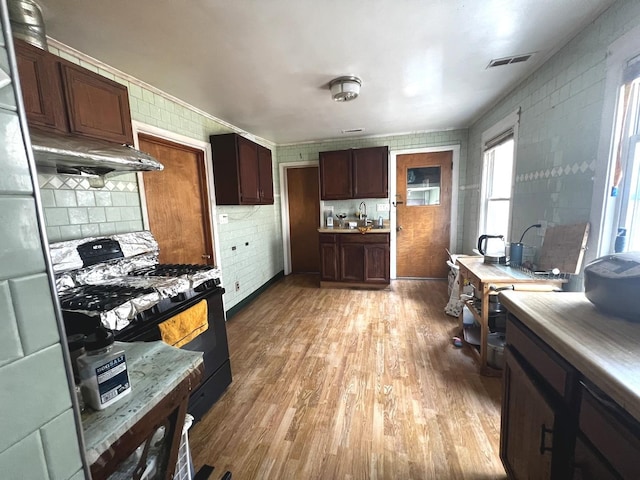 256 W 23rd Pl, Chicago, IL 60616 - kitchen featuring black gas stove, light wood-style floors, a sink, light countertops, and dark brown cabinets