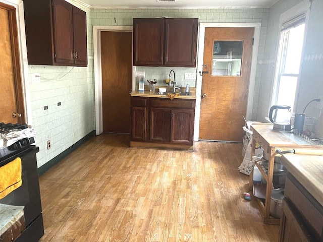 256 W 23rd Pl, Chicago, IL 60616 - kitchen featuring black range with gas stovetop, light wood finished floors, light countertops, and a sink