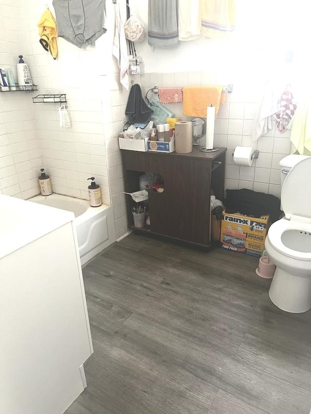 256 W 23rd Pl, Chicago, IL 60616 - bathroom featuring tile walls, toilet, wood finished floors, a tub to relax in, and vanity