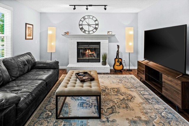 606 N Washington St, Hudson, IL 61748 - living area with wood finished floors, a brick fireplace, baseboards, and rail lighting