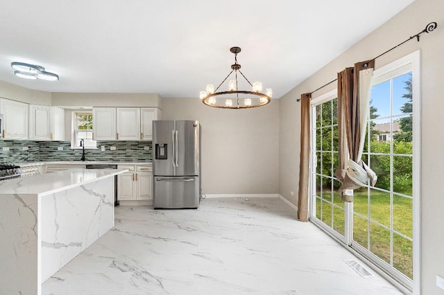 933 Tralee Ct, Gurnee, IL 60031 - kitchen featuring stainless steel appliances, decorative backsplash, a chandelier, light marble finish flooring, and light stone counters