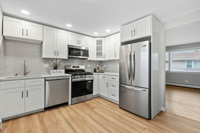 6964 W Diversey Ave Unit 7, Chicago, IL 60707 - kitchen featuring stainless steel appliances, a sink, a baseboard heating unit, light wood-style floors, and light countertops