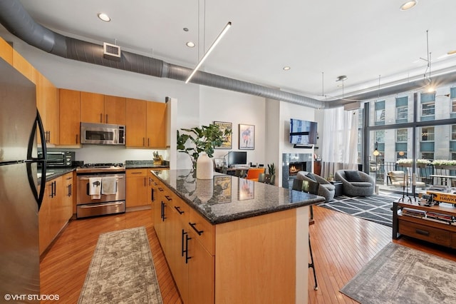 333 W Hubbard St Unit 708, Chicago, IL 60654 - kitchen with appliances with stainless steel finishes, light wood-style flooring, a center island, a tile fireplace, and recessed lighting