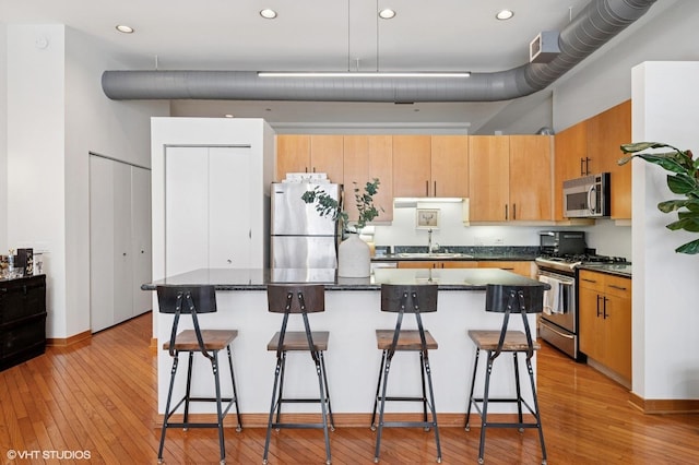 333 W Hubbard St Unit 708, Chicago, IL 60654 - kitchen featuring stainless steel appliances, light wood-style flooring, a breakfast bar area, a center island, and a towering ceiling