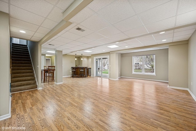 6 Valhalla Ct, Lake In The Hills, IL 60156 - unfurnished living room featuring a paneled ceiling, light wood finished floors, stairs, baseboards, and bar