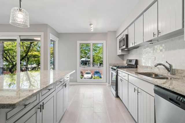 2717 S Michigan Ave, Chicago, IL 60616 - kitchen featuring stainless steel appliances, a sink, baseboards, decorative backsplash, and pendant lighting
