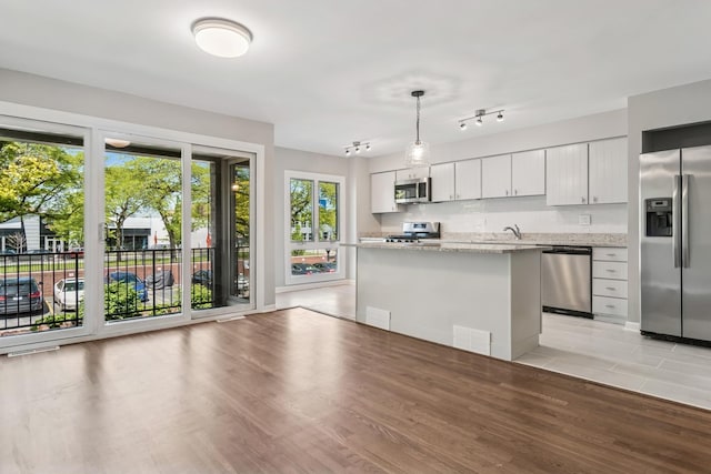 2717 S Michigan Ave, Chicago, IL 60616 - kitchen with stainless steel appliances, a center island, decorative light fixtures, light stone counters, and light wood-style floors