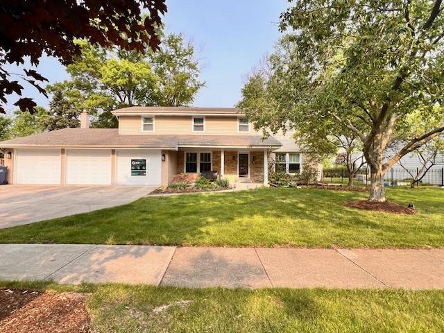 1716 Longvalley Dr, Northbrook, IL 60062 - traditional home featuring an attached garage, concrete driveway, a chimney, and a front lawn