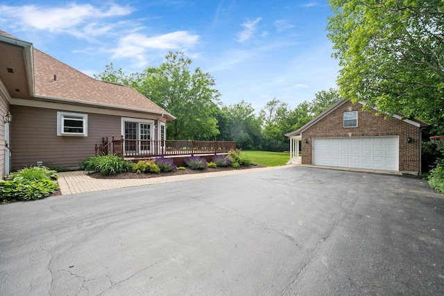 6099 Polo Club Dr, Yorkville, IL 60560 - view of side of property with a wooden deck, a garage, driveway, brick siding, and a shingled roof