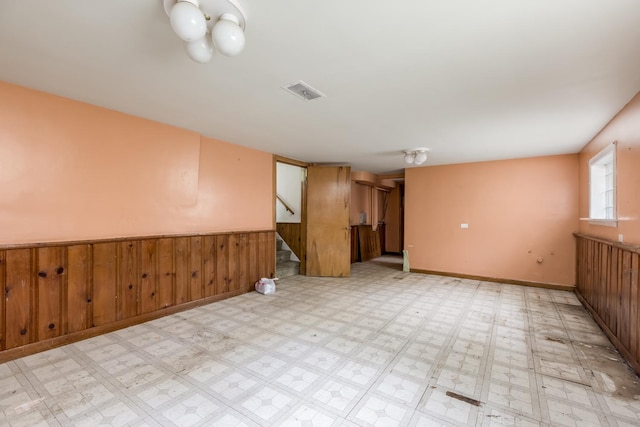 1808 Laurel Ave, Evanston, IL 60201 - empty room with stairs, light flooring, wainscoting, and wooden walls