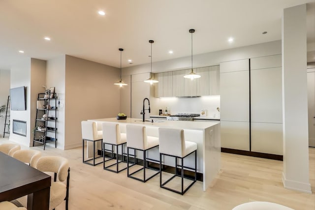 613 N Ogden Ave Unit 4W, Chicago, IL 60642 - kitchen featuring modern cabinets, light wood-style floors, a kitchen island with sink, a kitchen bar, and light countertops