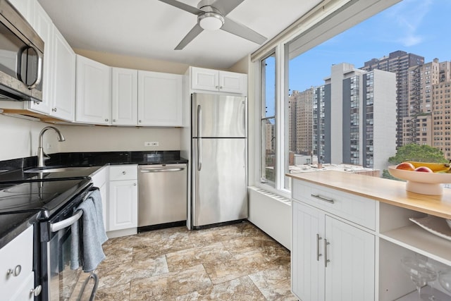 1400 N State Pkwy Unit 9F, Chicago, IL 60610 - kitchen with appliances with stainless steel finishes, white cabinetry, a city view, ceiling fan, and light stone finish flooring