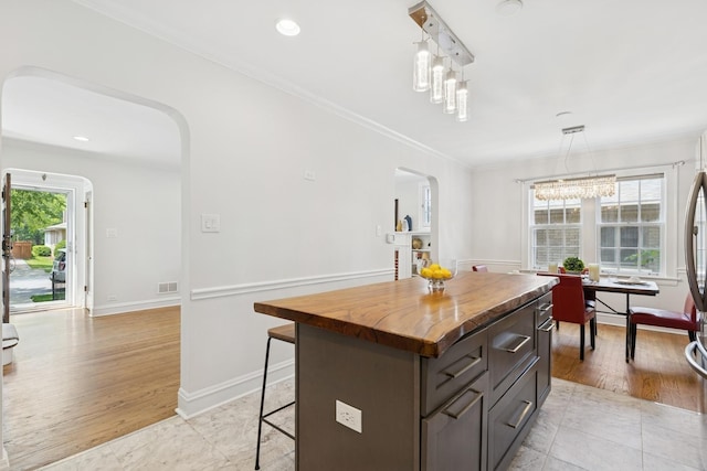8335 Kostner Ave, Skokie, IL 60076 - kitchen featuring arched walkways, wood counters, a kitchen breakfast bar, a kitchen island, and crown molding