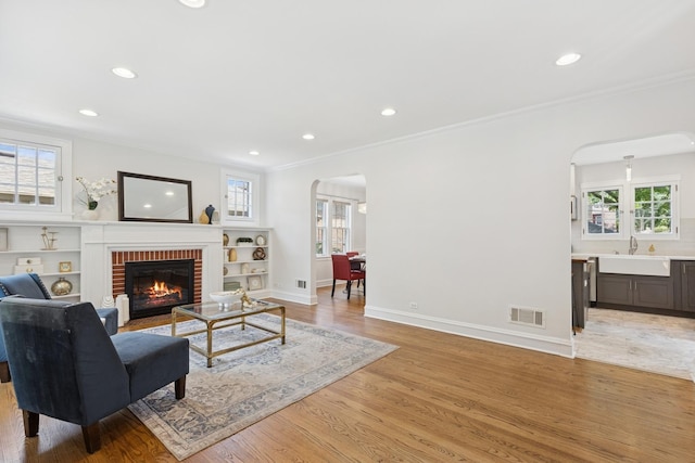 8335 Kostner Ave, Skokie, IL 60076 - living area featuring arched walkways, recessed lighting, crown molding, a brick fireplace, and light wood-style flooring