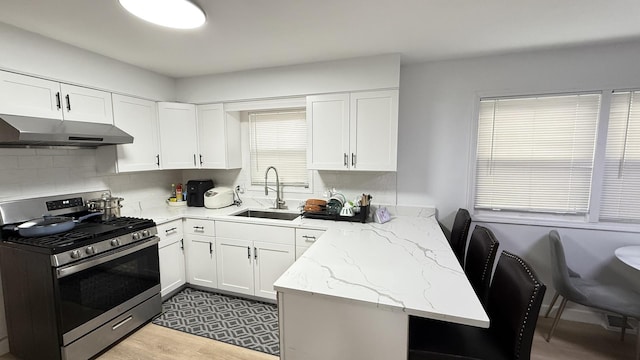 532 W 27th St, Chicago, IL 60616 - kitchen featuring stainless steel range with gas stovetop, a sink, under cabinet range hood, and white cabinetry