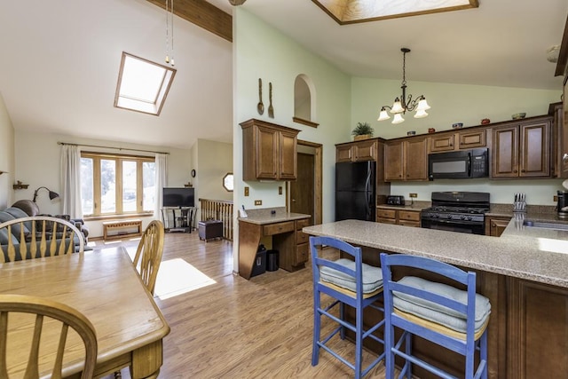 33061 N Rolling Hills Rd, Grayslake, IL 60030 - kitchen with black appliances, a chandelier, high vaulted ceiling, light wood finished floors, and a peninsula