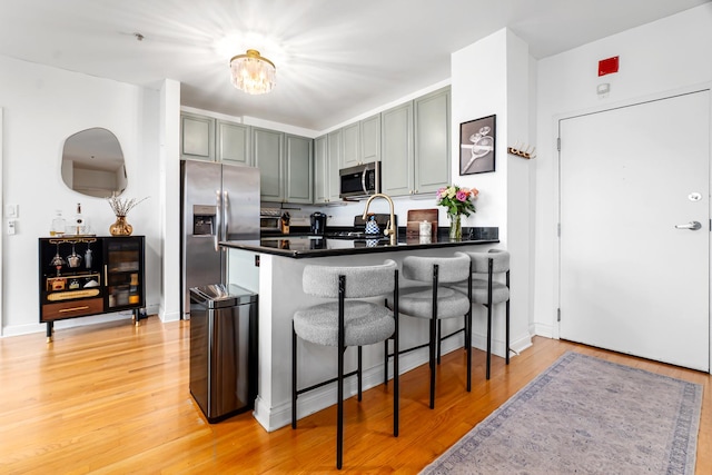 1444 N Orleans St Unit 6C, Chicago, IL 60610 - kitchen with appliances with stainless steel finishes, dark countertops, a peninsula, light wood-type flooring, and a breakfast bar