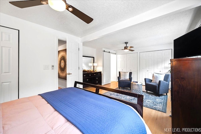 636 Cambridge Dr, Schaumburg, IL 60193 - bedroom featuring wood finished floors, multiple closets, a textured ceiling, a barn door, and a ceiling fan