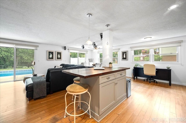 636 Cambridge Dr, Schaumburg, IL 60193 - kitchen with butcher block countertops, a textured ceiling, open floor plan, a ceiling fan, and a kitchen bar