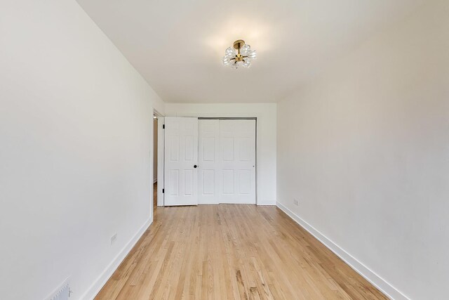 839 N Kildare Ave, Chicago, IL 60651 - unfurnished bedroom with baseboards, a chandelier, light wood finished floors, and a closet