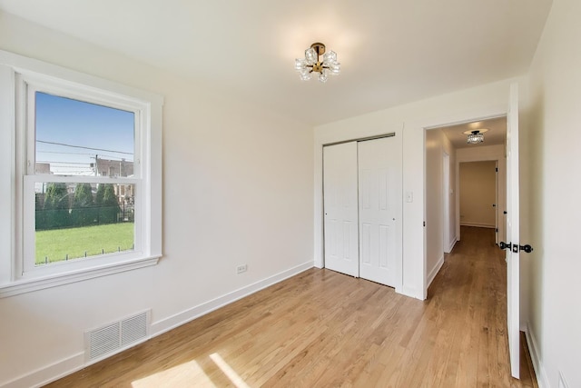 839 N Kildare Ave, Chicago, IL 60651 - unfurnished bedroom featuring a closet, light wood-style floors, baseboards, and a chandelier