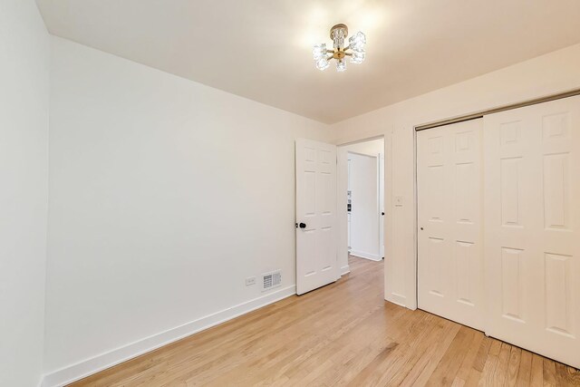 839 N Kildare Ave, Chicago, IL 60651 - unfurnished bedroom featuring light wood-type flooring, baseboards, a chandelier, and a closet