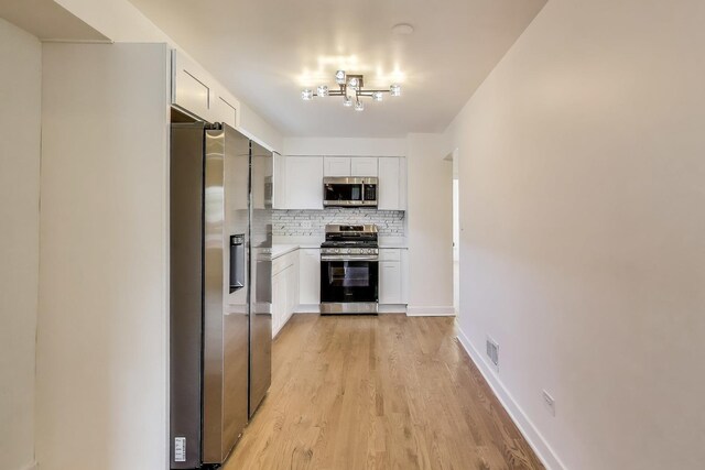 839 N Kildare Ave, Chicago, IL 60651 - kitchen with stainless steel appliances, tasteful backsplash, white cabinetry, light wood-style flooring, and light countertops