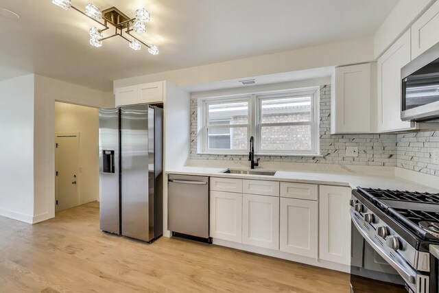 839 N Kildare Ave, Chicago, IL 60651 - kitchen with stainless steel appliances, a sink, backsplash, and white cabinets