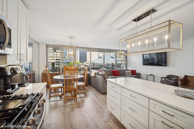 400 E Randolph St Unit 826, Chicago, IL 60601 - kitchen featuring a chandelier, appliances with stainless steel finishes, light wood-style floors, white cabinets, and light stone counters