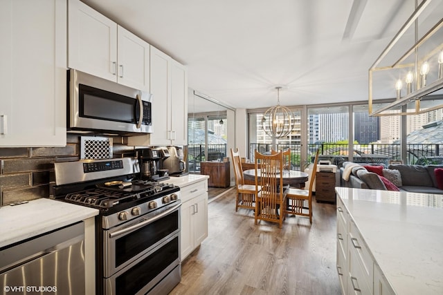 400 E Randolph St Unit 826, Chicago, IL 60601 - kitchen with appliances with stainless steel finishes, a chandelier, light wood-style flooring, and white cabinetry