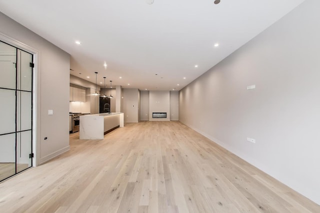 613 N Ogden Ave Unit 2E, Chicago, IL 60642 - unfurnished living room with a sink, light wood-type flooring, recessed lighting, and baseboards