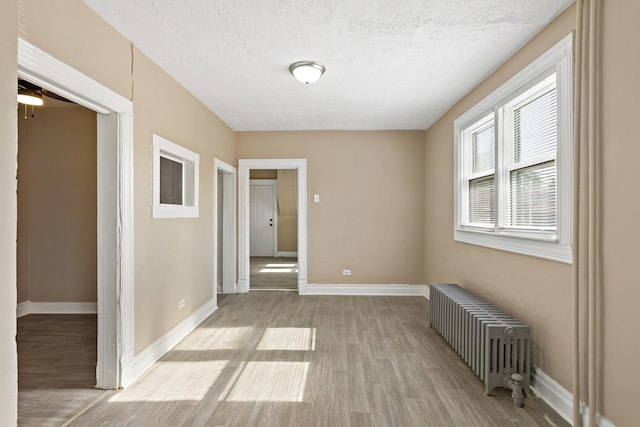 161 E 25th St, Chicago Heights, IL 60411 - empty room with radiator, light wood-type flooring, baseboards, and a textured ceiling