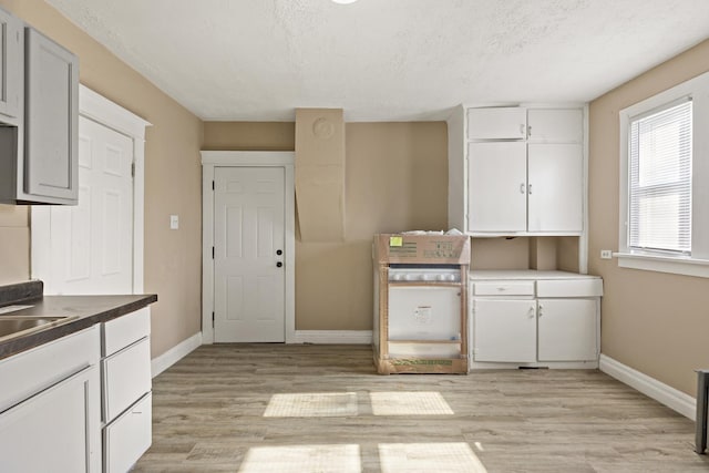 161 E 25th St, Chicago Heights, IL 60411 - kitchen with baseboards, light wood-type flooring, a textured ceiling, and white cabinetry