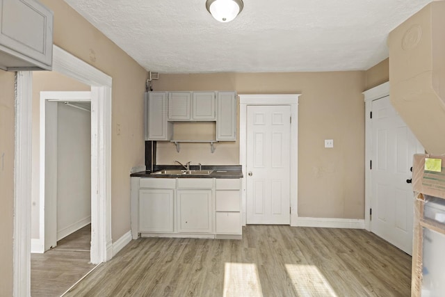 161 E 25th St, Chicago Heights, IL 60411 - kitchen featuring a sink, light wood-style floors, baseboards, dark countertops, and a textured ceiling