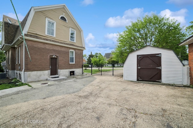 558 N Crystal St, Elgin, IL 60123 - view of property exterior with a gambrel roof, brick siding, a storage unit, and a shingled roof