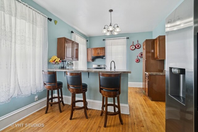 558 N Crystal St, Elgin, IL 60123 - kitchen with appliances with stainless steel finishes, under cabinet range hood, a peninsula, a kitchen bar, and light wood-type flooring