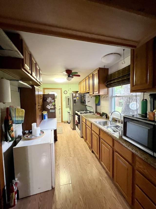 2110 N Mobile Ave, Chicago, IL 60639 - kitchen featuring stainless steel appliances, light wood-type flooring, ceiling fan, and brown cabinets