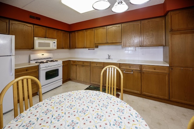 7021 W Touhy Ave Unit 305, Niles, IL 60714 - kitchen featuring white appliances, a sink, light floors, light countertops, and brown cabinets