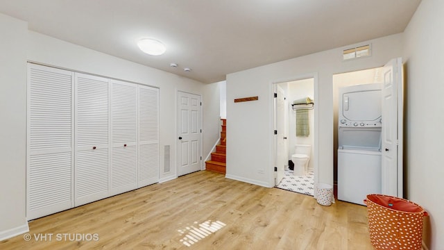 3649 W Cornelia Ave Unit C, Chicago, IL 60618 - unfurnished bedroom with stacked washer / drying machine, light wood-style floors, connected bathroom, baseboards, and a closet