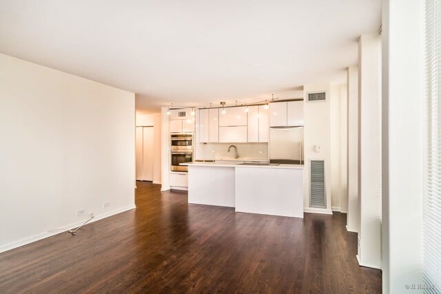 100 E Walton St Unit 22H, Chicago, IL 60611 - kitchen featuring fridge, double oven, white cabinetry, dark wood-type flooring, and light countertops